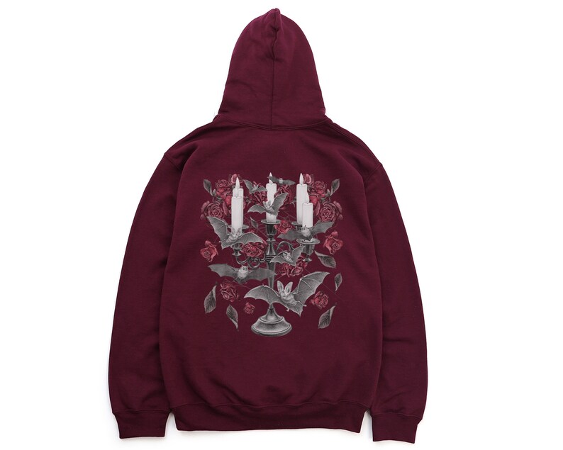 May include: Burgundy hooded sweatshirt with a graphic print of a candelabra with bats and roses. The candelabra has three candles and is surrounded by bats and roses.