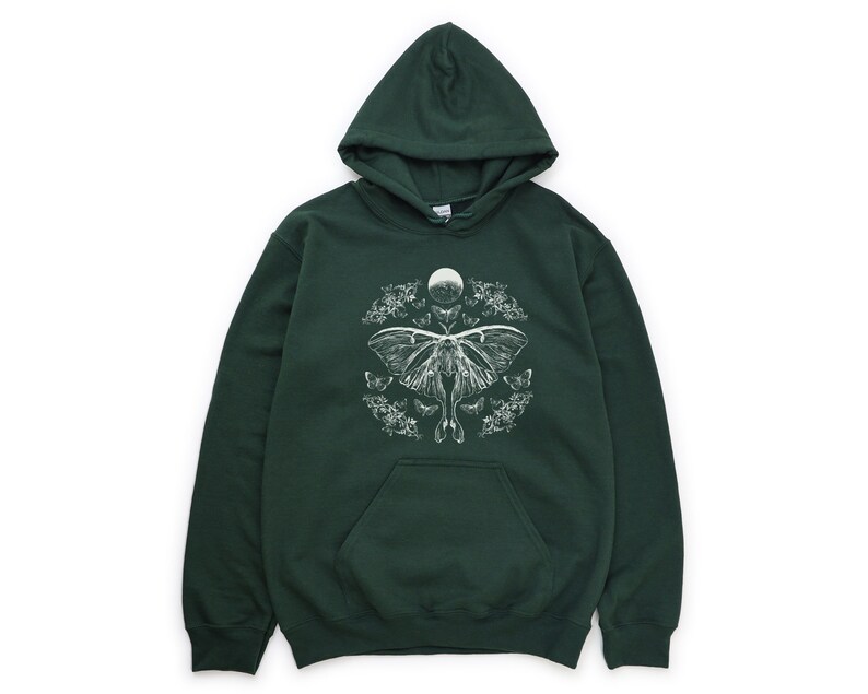 May include: A dark green hooded sweatshirt featuring a white print of a moth and moon design. The moth is surrounded by smaller moths and floral elements.