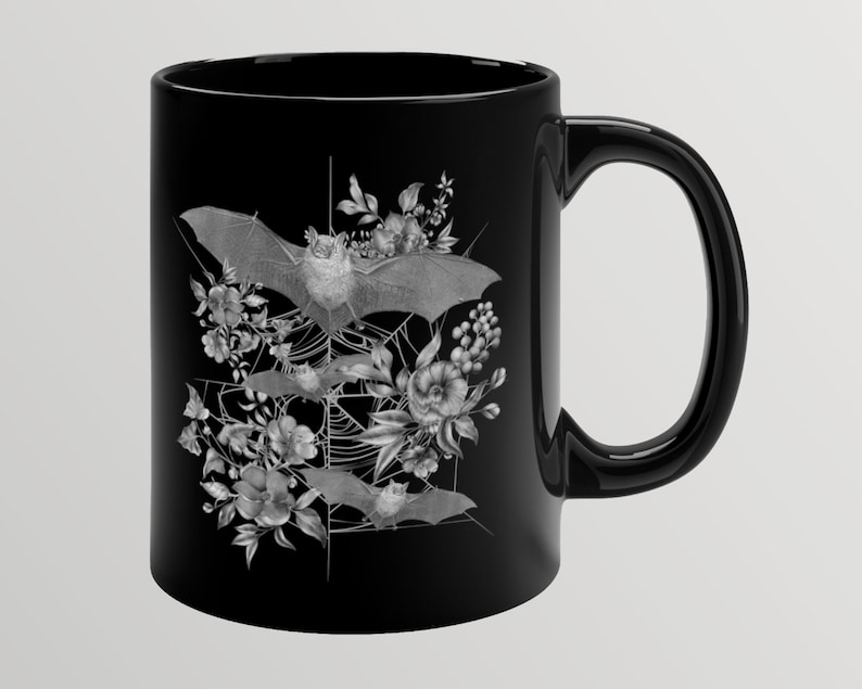 May include: Black ceramic mug with a white design of bats flying through a spiderweb with flowers.
