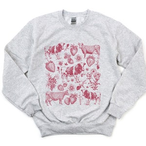May include: A gray sweatshirt with a red print of cows and strawberries. The print is a vintage style illustration.