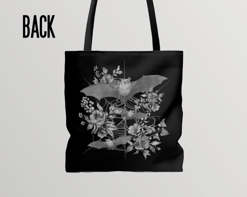 May include: Black tote bag with a white design of bats and flowers. The bats are flying in a web pattern with flowers and leaves around them.