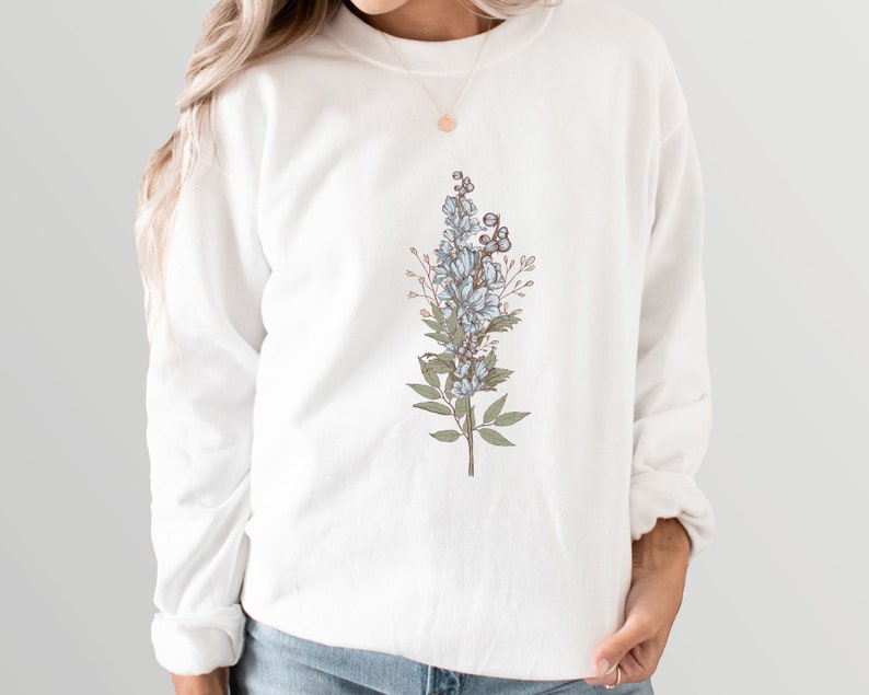 May include: White sweatshirt with a floral design featuring blue flowers and green leaves.