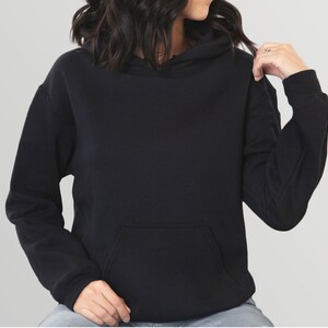 May include: A black hoodie with a kangaroo pocket and a drawstring hood. The long-sleeved sweatshirt is made of a soft material and is a solid color.