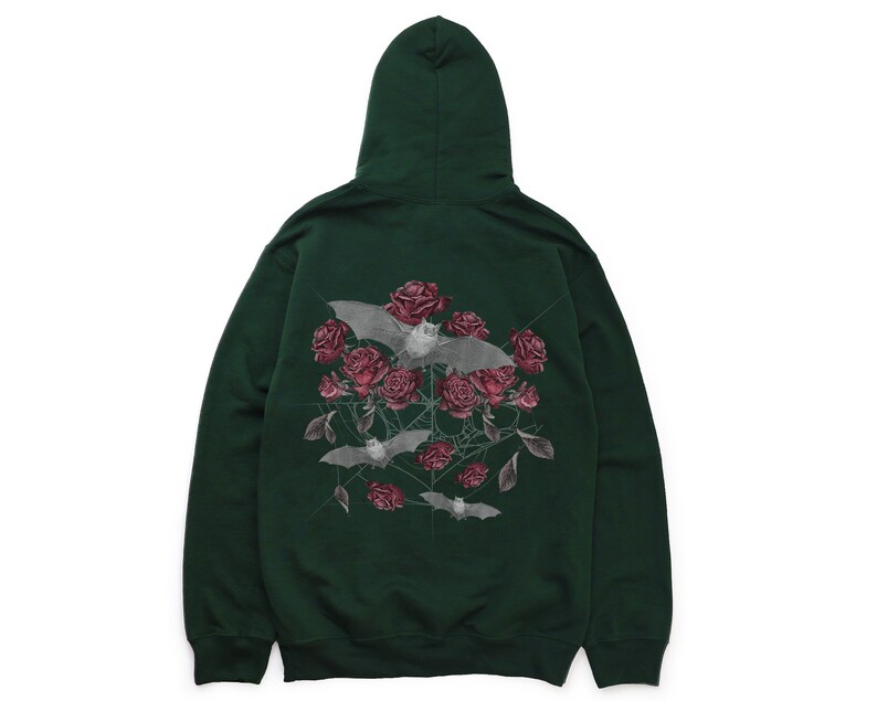 May include: Dark green hoodie featuring a graphic of bats, roses, and spiderwebs. The bats are gray, and the roses are a deep red. The hoodie has a hood and a front pocket.