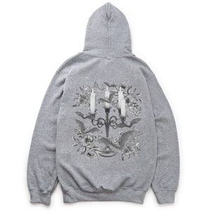 May include: Grey hooded sweatshirt with a black and white graphic print of a candelabra with candles and bats surrounded by flowers.