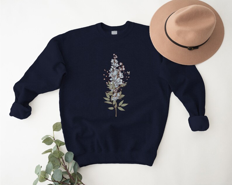 May include: A navy blue sweatshirt with a floral design featuring white flowers and green leaves.