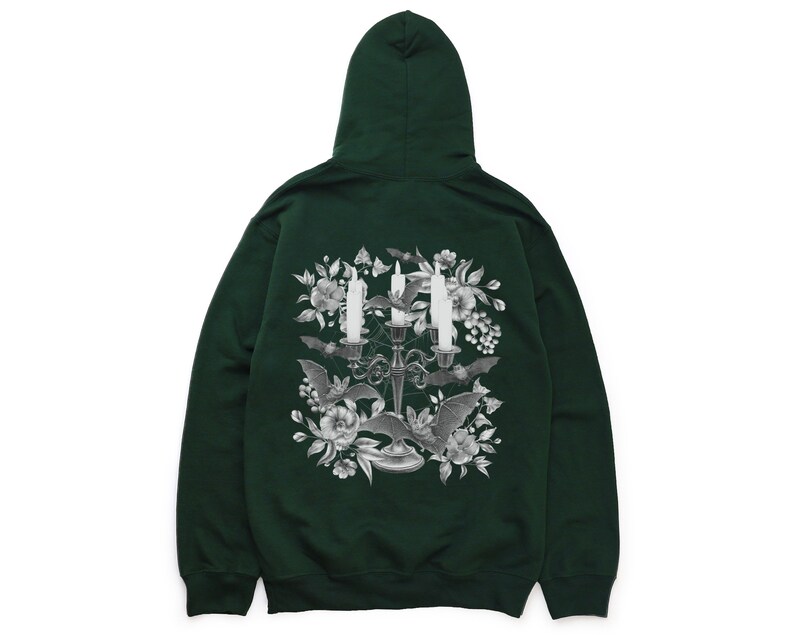 May include: A dark green hooded sweatshirt featuring a graphic print of a candelabra with three candles, bats, and flowers. The graphic is in shades of grey.
