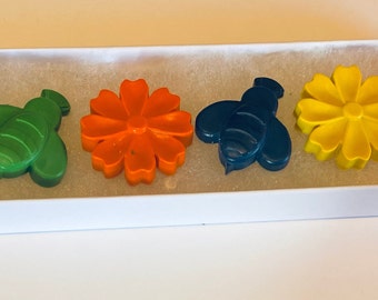 May include: A set of six colorful crayons shaped like bees and flowers. The crayons are red, green, orange, blue, yellow, and pink.