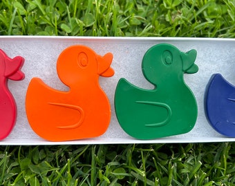 May include: Four rubber duck bath toys in a white box. The ducks are red, orange, green, and blue.