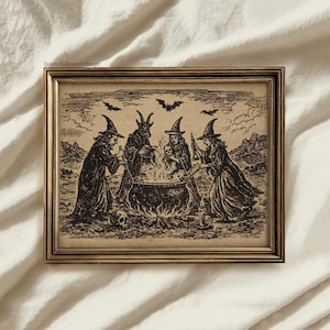 May include: A framed vintage print depicting a witch's cauldron scene. Four figures in witch hats and robes surround a bubbling cauldron over a fire. Bats fly in the sky above the scene. The print is in a gold-colored frame.