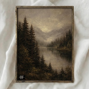 May include: A framed landscape painting showing a tranquil lake scene with evergreen trees and mountains. The artwork uses a muted palette of greens, browns, and greys, with a vintage style. The frame has a metallic finish.