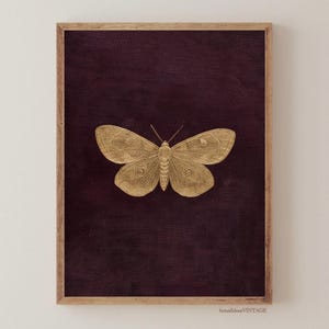 May include: A framed print featuring a gold-colored butterfly against a deep purple background. The butterfly is centered, with detailed wing patterns. The frame is a light brown color. The print has a vintage aesthetic.