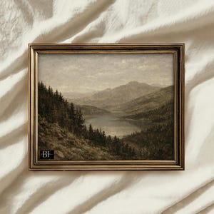 Peut inclure: Peinture de paysage encadrée représentant un lac paisible entouré de collines et de montagnes. L'œuvre d'art est réalisée dans des tons sourds de brun, de gris et de vert, avec un cadre doré. La peinture évoque la tranquillité et la beauté naturelle.