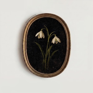 Puede incluir: Obra de arte enmarcada de forma ovalada que presenta una ilustración botánica de dos flores de campanillas blancas con tallos verdes sobre un fondo negro. El marco es dorado con un diseño texturizado. La obra está montada en una pared blanca.