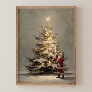 以下が含まれることがあります： 額縁に入ったヴィンテージのクリスマスプリント。このアートワークは、金色の光と星で照らされた雪に覆われたクリスマスツリーを描いています。サンタクロースは赤い衣装を着て近くに立っており、木に向かって手を伸ばしています。