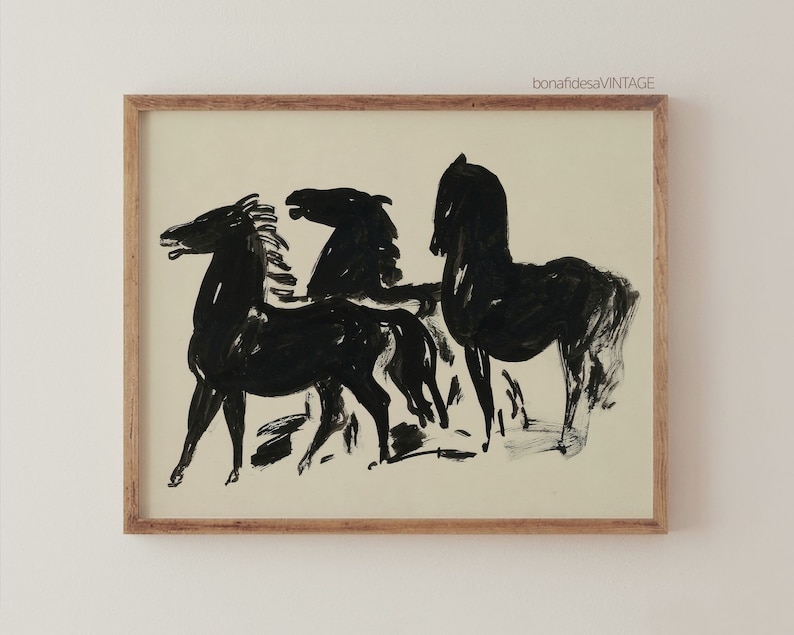 May include: Black and white ink drawing of three horses in a minimalist style. The horses are depicted in a simple, abstract manner, with their bodies and heads outlined in black ink. The drawing is framed in a light wood frame.