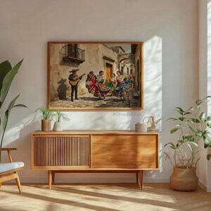 May include: A rectangular framed wall art print depicting a scene of a musician playing a guitar while three individuals in colorful, multi-layered dresses dance on a cobblestone street in front of beige buildings with a balcony and archway.