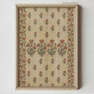 May include: A framed artwork with a beige backdrop and a repeating floral design in orange, red, and green. The artwork has a floral border. The frame is a light beige colour. Thebonafidesa is written in the top right corner.