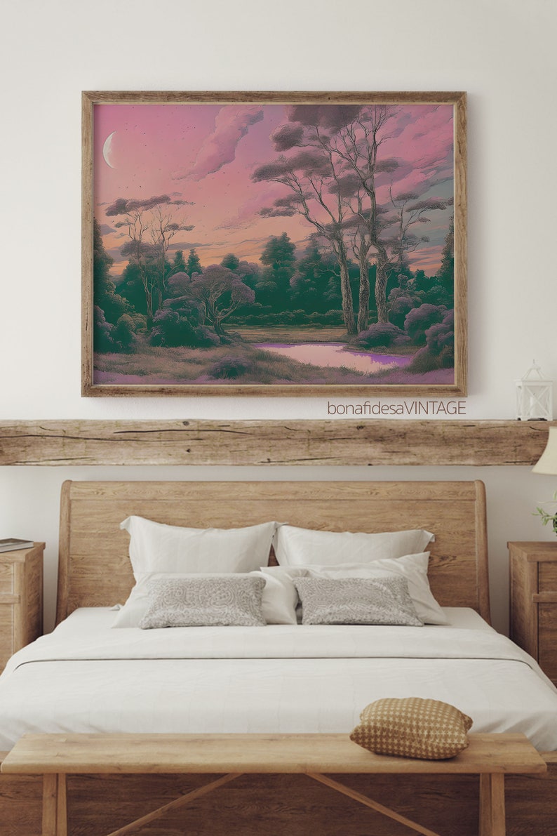 May include: A framed print of a landscape painting depicting a forest scene with a river and a crescent moon in the sky. The sky is a soft pink and purple color, and the trees are a deep green. The painting is in a wooden frame.