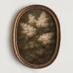 Op de afbeelding: Een ovaalvormige ingelijste prent met een gedetailleerde botanische illustratie van witte seringenbloesems. Het kunstwerk heeft een vintage esthetiek, met een donkere achtergrond en een goudkleurige lijst. De afbeelding is een klassiek bloemontwerp.