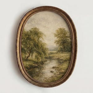 May include: An oval-shaped framed landscape painting. The artwork depicts a serene river scene with trees and grassy banks. The frame is a detailed, ornate gold color. The painting has a vintage aesthetic.