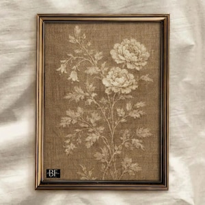 May include: A framed botanical print featuring a floral design in shades of beige and cream. The artwork is set within a dark brown, rectangular frame. The print showcases a detailed illustration of flowers and foliage, creating a vintage aesthetic.
