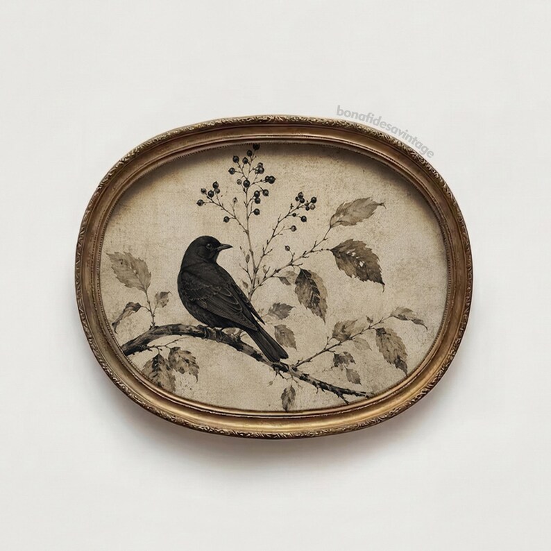 Peut inclure: Une &oelig;uvre d'art murale de forme ovale repr&eacute;sentant un oiseau noir perch&eacute; sur une branche avec des feuilles et des baies. L'illustration est encadr&eacute;e dans un cadre en or m&eacute;tallique. Le texte bonafidesavintage est imprim&eacute; en haut &agrave; droite.