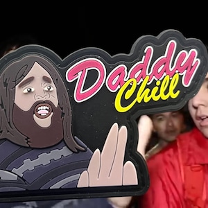 May include: A black patch with the text "Daddy Chill" in pink and yellow lettering. The patch features a cartoon illustration of a man with a beard and long hair, wearing a striped shirt and making a hand gesture.
