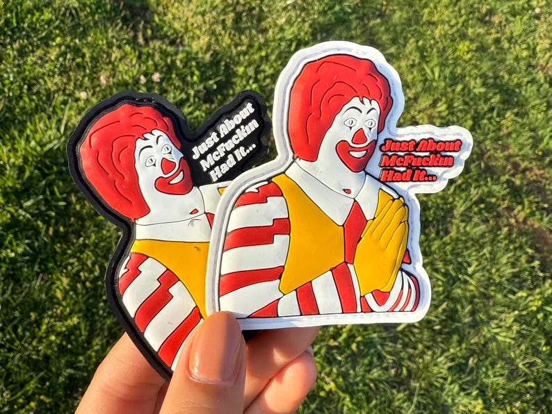 K&ouml;nnte beinhalten: Zwei wei&szlig;-rot gestreifte Patches mit einem Cartoon-Bild von Ronald McDonald. Die Patches haben schwarze R&auml;nder und den Text "Just About McFuckin Had It..." aufgedruckt.
