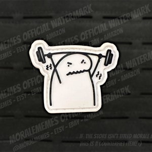 Könnte beinhalten: Weißer Patch mit schwarzem Umriss einer Strichmännchenfigur, die eine Langhantel hebt. Die Strichmännchenfigur hat einen verzweifelten Ausdruck. Der Patch hat einen schwarzen Rand.