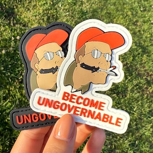 May include: Two white and black embroidered patches featuring a cartoon character wearing a red hat and sunglasses. The character is holding a knife in one hand and a cigarette in the other. The text on the patches reads "Become Ungovernable".