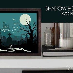 May include: A digital file for a shadow box craft project featuring a spooky Halloween scene with a haunted house, a graveyard, bats, and a full moon. The file is in SVG format.