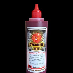 Op de afbeelding: Een fles van 250ml magenta DTF-inkt met een rode draaidop. Het etiket bevat een cartoonfiguur van een dynamietstaaf, de tekst DYNAMITE DTF, MAGENTA DTF INK, 250ML, de slogan MAKE YOUR PRINTS EXPLODE en technische opslaginstructies.