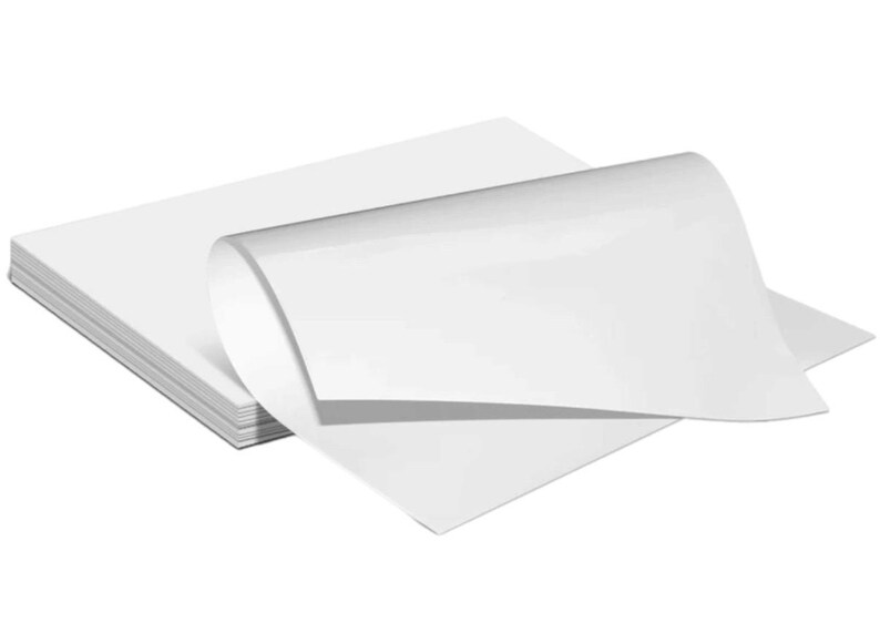 May include: A stack of white paper sheets, with one sheet folded over to reveal the smooth, white surface of the paper.