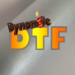 May include: A silver glitter background with the text "Dynamite DTF" in yellow and orange letters. The text is outlined in black.