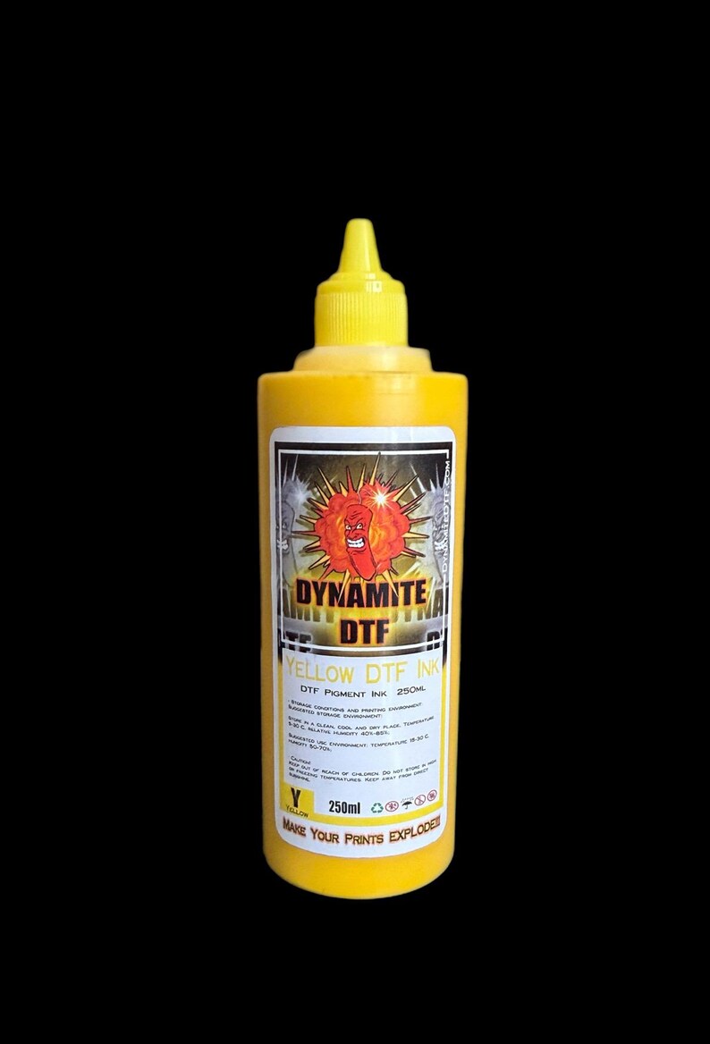 Op de afbeelding: Een gele plastic knijpfles met 250ml Dynamite DTF gele pigmentinkt. Het etiket bevat een cartoonfiguur van een dynamietstaaf, de tekst DYNAMITE DTF, de slogan MAKE YOUR PRINTS EXPLODE en instructies voor opslag en gebruik.