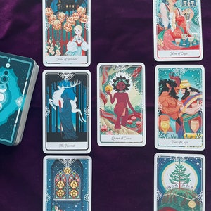 Peut inclure: &Eacute;talement de cartes de tarot avec neuf cartes, dont L'Ermite, Neuf de B&acirc;tons, Reine de Pi&egrave;ces, Deux de Coupes, Neuf de Coupes, Roi de Pi&egrave;ces et Cinq de Pi&egrave;ces. Les cartes sont illustr&eacute;es d'images color&eacute;es et pr&eacute;sentent une vari&eacute;t&eacute; de personnages et de symboles.