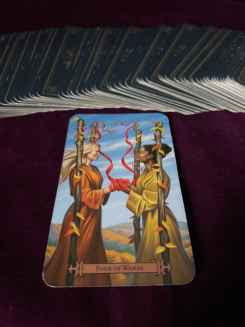 May include: Tarot card depicting the Four of Wands card. Two people are holding hands, standing in front of four wands with red ribbons tied around them. The background is a blue sky with white clouds and a landscape of green hills and trees. The card is titled "Four of Wands".