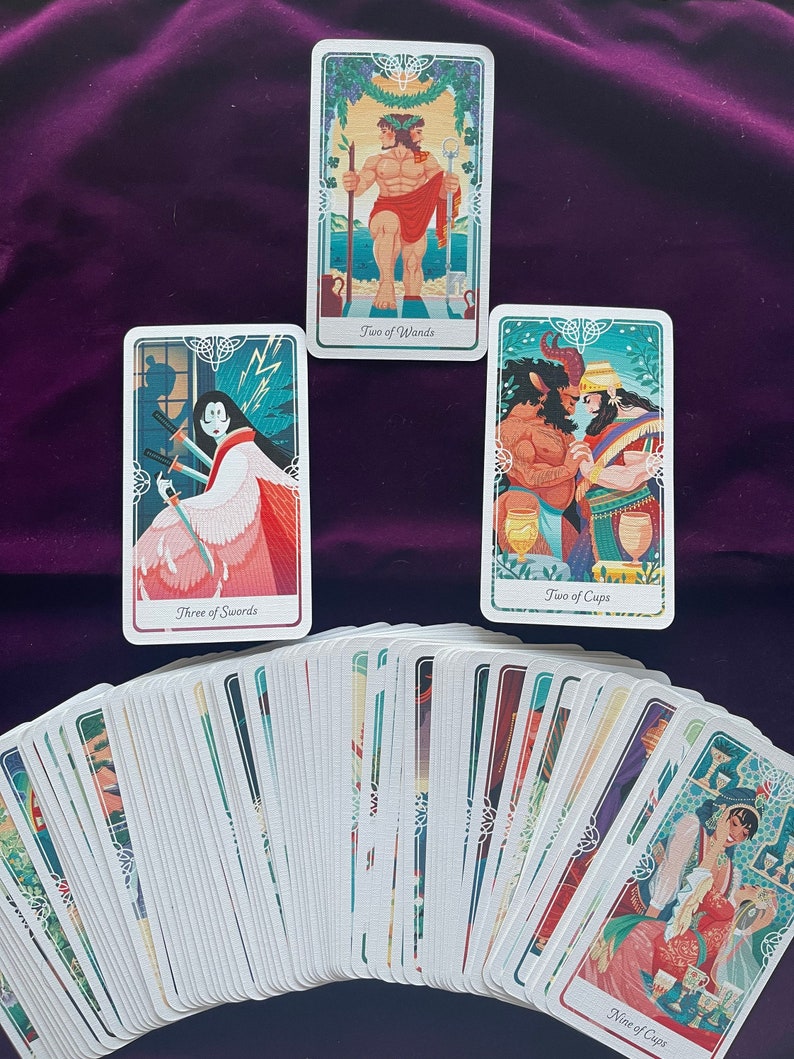 Peut inclure: Un jeu de cartes de tarot avec un &eacute;talement de cartes montrant le Deux de B&acirc;tons, le Trois d'&Eacute;p&eacute;es, le Deux de Coupes et le Neuf de Coupes. Les cartes sont illustr&eacute;es d'images color&eacute;es et ont une bordure verte et blanche.