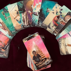May include: A spread of tarot cards on a burgundy surface. The cards are arranged in a semi-circle with the "The Hierophant" card in the center. The cards feature colorful illustrations and text.