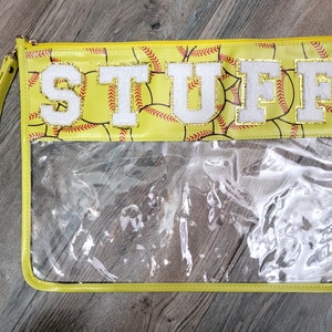 May include: Yellow zippered pouch with a clear plastic window. The pouch has a softball pattern and the word "STUFF" in white letters with gold glitter trim.