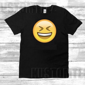 May include: Black t-shirt with a yellow emoji face with a big smile and squinting eyes.