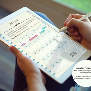 May include: A digital planner displayed on a tablet, featuring a calendar layout for January. The screen shows dates, with some highlighted and labeled. A stylus is used to interact with the planner. Text on the screen includes "MONTHLY SUMMARY".