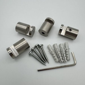 Puede incluir: Un juego de cuatro soportes para carteles de metal plateado con un inserto de plástico transparente, cuatro tacos de plástico blanco, cuatro tornillos plateados y una llave Allen plateada.