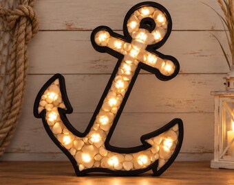May include: A black anchor-shaped decorative light fixture filled with small, smooth white stones. The interior of the anchor is illuminated by warm white LED lights that shine through the gaps between the stones, creating a soft glow.
