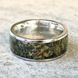 May include: A silver ring with a green and brown camouflage pattern inlay.