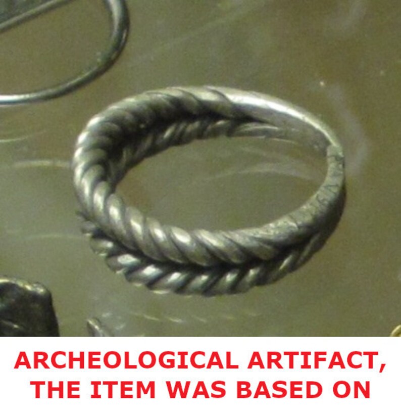 May include: A silver ring with a twisted rope design. The ring is an archeological artifact.