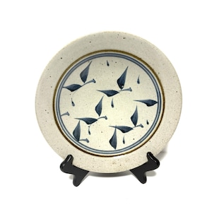 May include: A white ceramic plate with a blue and brown design of stylised leaves. The plate is on a black stand.