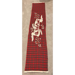 May include: A long rectangular table runner featuring a red, black, and green plaid pattern. The center displays an off-white fabric banner with the embroidered text Oh Holy Night, surrounded by embroidered white berry sprigs and leaves.