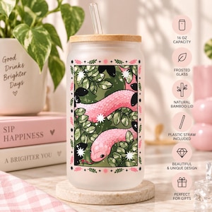 May include: A frosted glass tumbler with a 473 ml capacity, featuring a natural bamboo lid and a clear plastic straw. The glass displays a rectangular graphic of a pink snake winding through green leaves and white star accents, framed by a border.